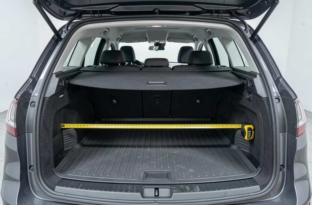 Intérieur du coffre de la Peugeot 308 SW avec mètre ruban mesurant la largeur du plancher de chargement, vue documentaire depuis l'intérieur du véhicule