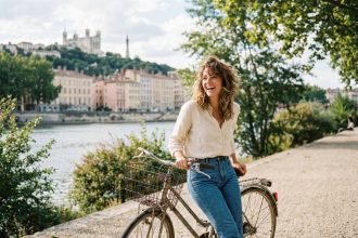 Jeune femme souriante à vélo près du Rhône à Lyon