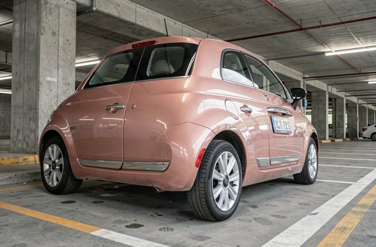 Arrière de la Fiat 500 rose gold dans un parking urbain, détails de la peinture métallique et des finitions chromées