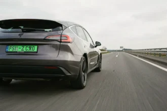 Voiture électrique avec plaque verte roulant sur autoroute française, vue de derrière en angle bas