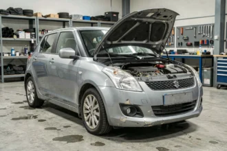 Suzuki Swift 1.3 DDIS dans un atelier mécanique, vue 3/4 avant avec capot entrouvert sur le moteur diesel