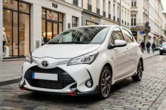 Toyota Yaris Sport blanche garée dans une rue urbaine moderne, vue en angle 3/4 avant mettant en valeur son design sportif