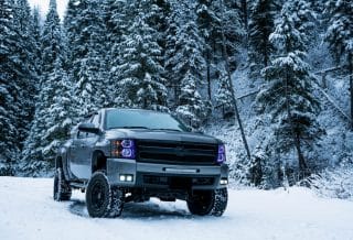 gray pickup truck on snow field surrounded by trees