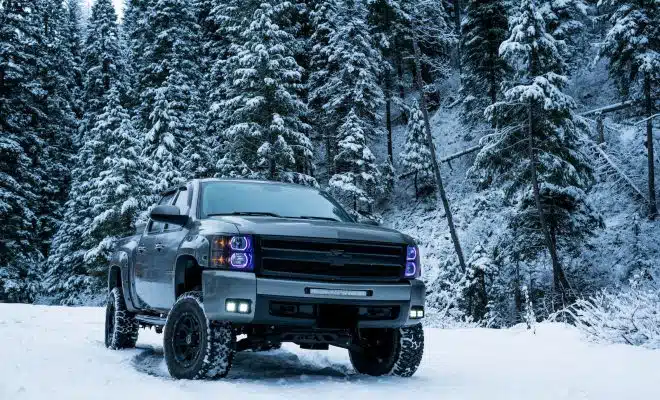 gray pickup truck on snow field surrounded by trees